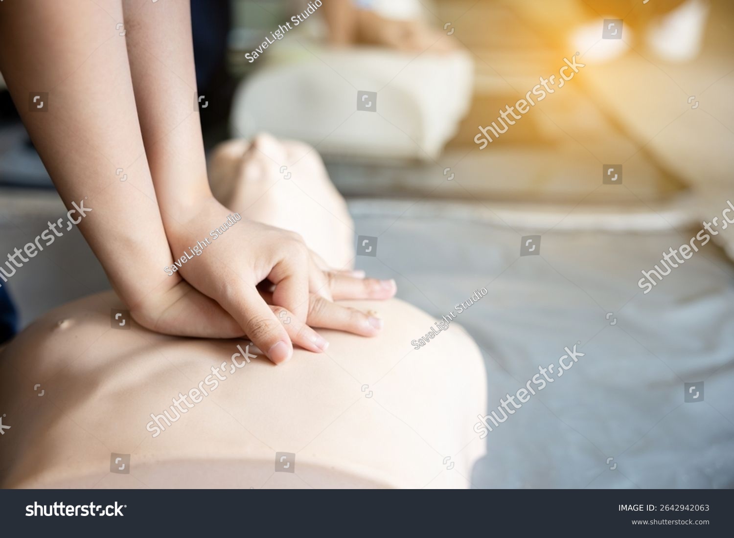 Hands performing chest compressions on a CPR manikin