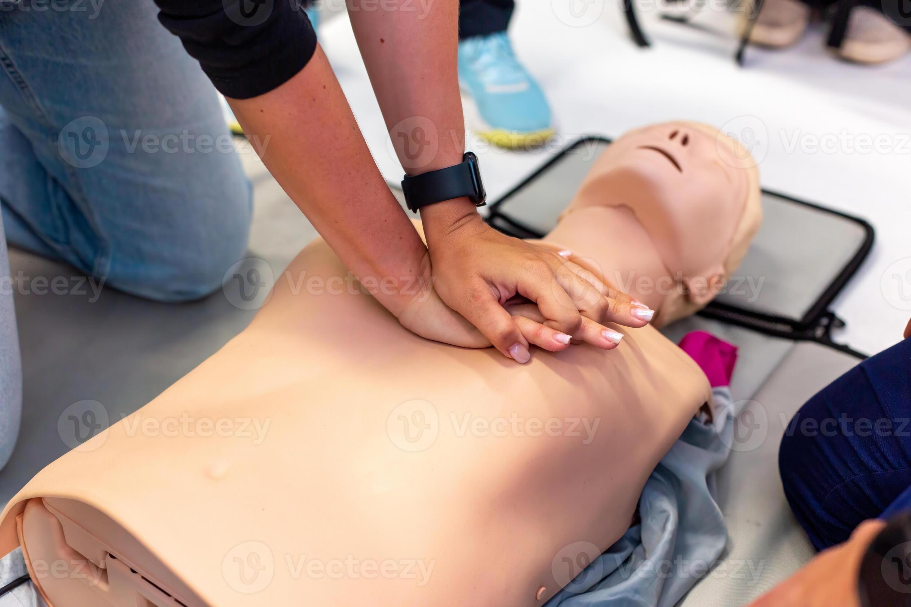 Hands performing CPR on a training manikin